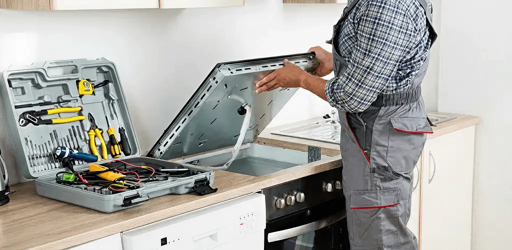 Handyman repairing a cooktop and checking wiring connections in Aurora, CO