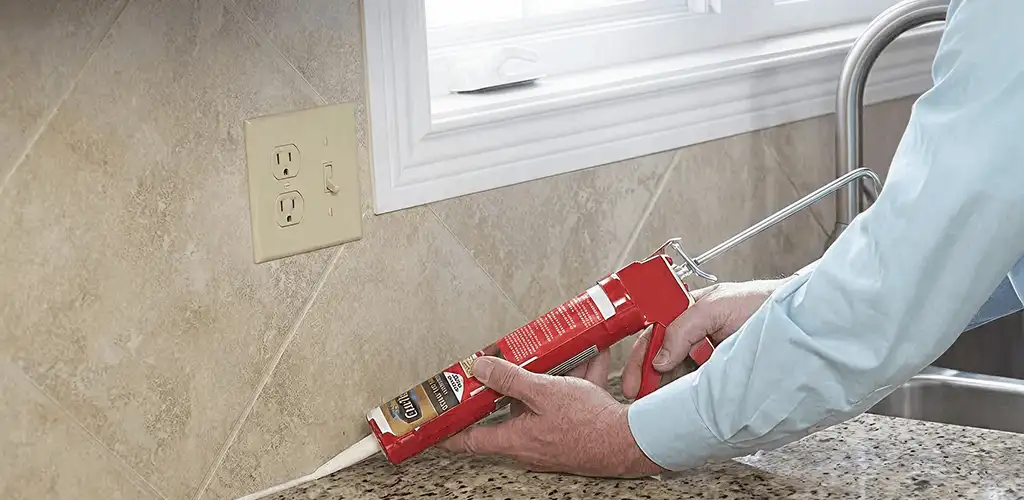 Handyman applying caulk along a kitchen backsplash and countertop seam in Aurora, CO