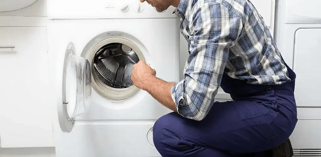 Handyman inspecting a dryer drum and internal parts for repair in Aurora, CO