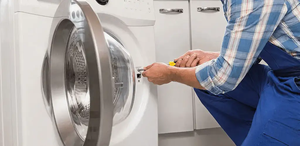 Handyman repairing a clothes dryer and checking electrical connections in Aurora, CO