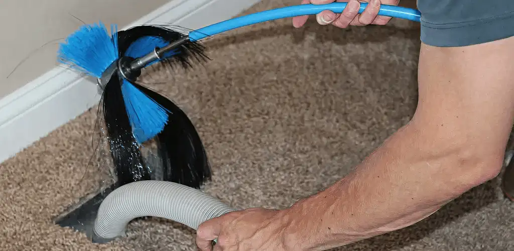 Dryer vent cleaning technician brushing lint from a vent line in Aurora, CO