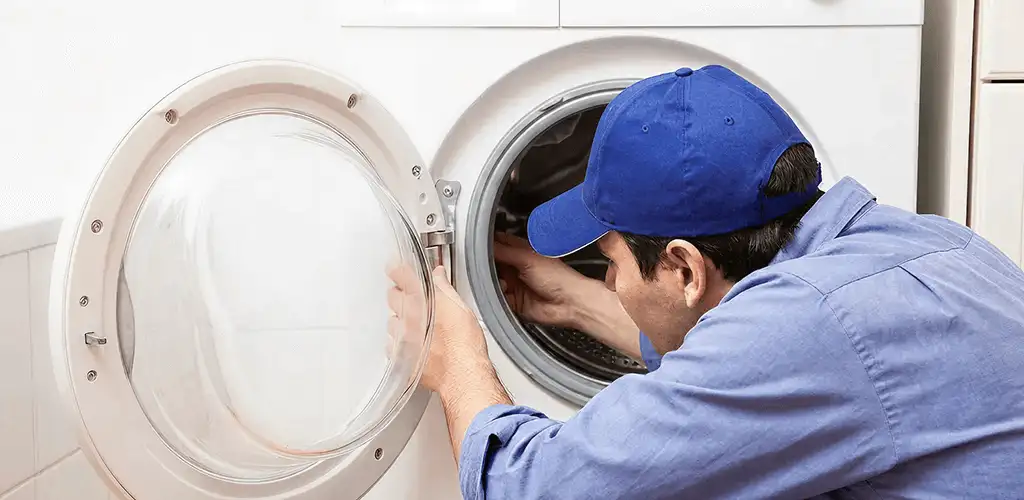 Washing machine repair handyman inspecting a front-load washer drum in Aurora, CO