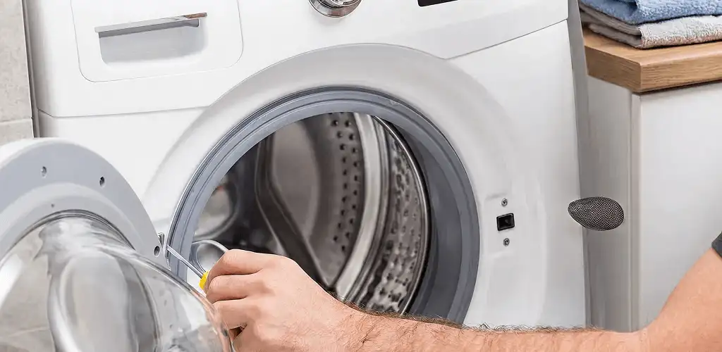 Handyman repairing a front-load washing machine and inspecting the drum in Aurora, CO