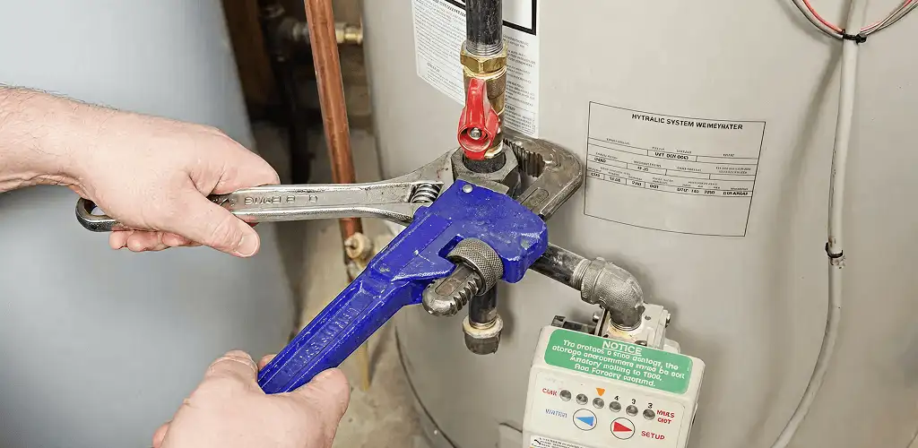 Water heater repair technician tightening the shutoff valve and supply line in Aurora, CO